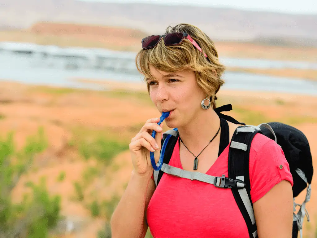 woman using hydration bladder while hiking