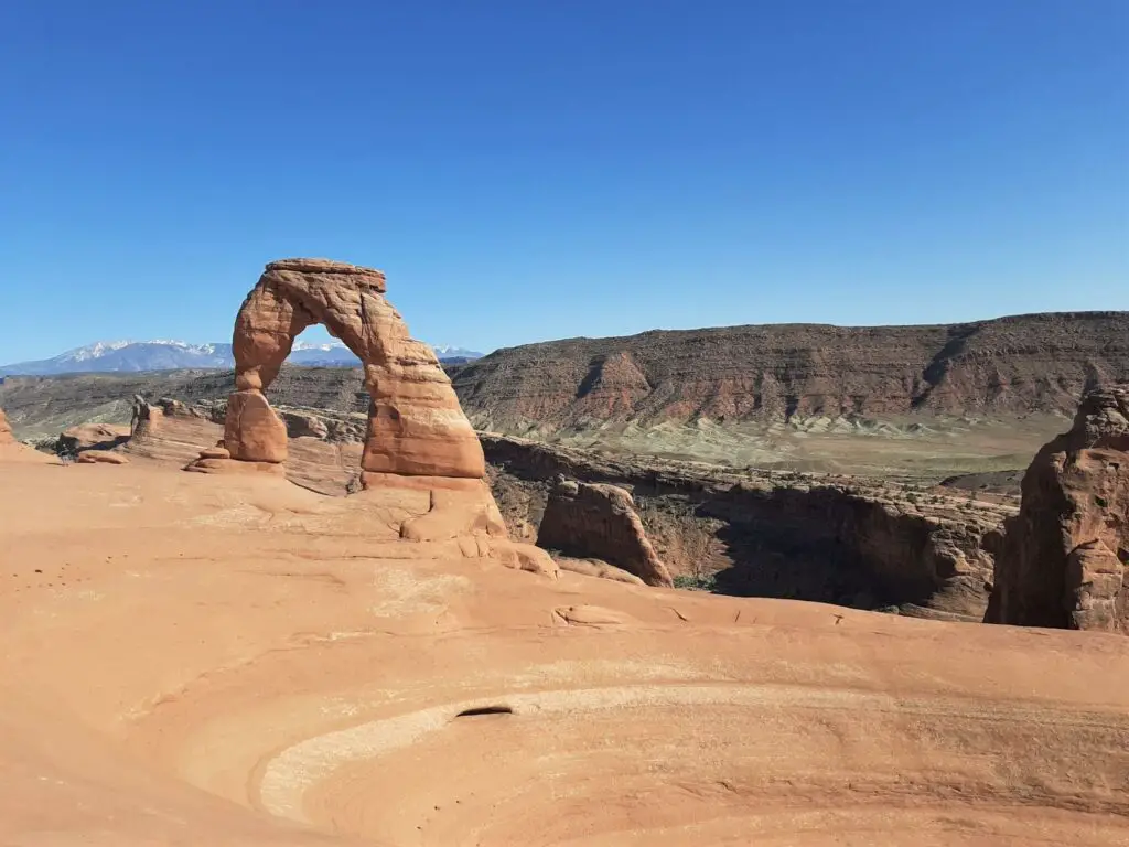 delicate arch with snow-capped mountains in the distance